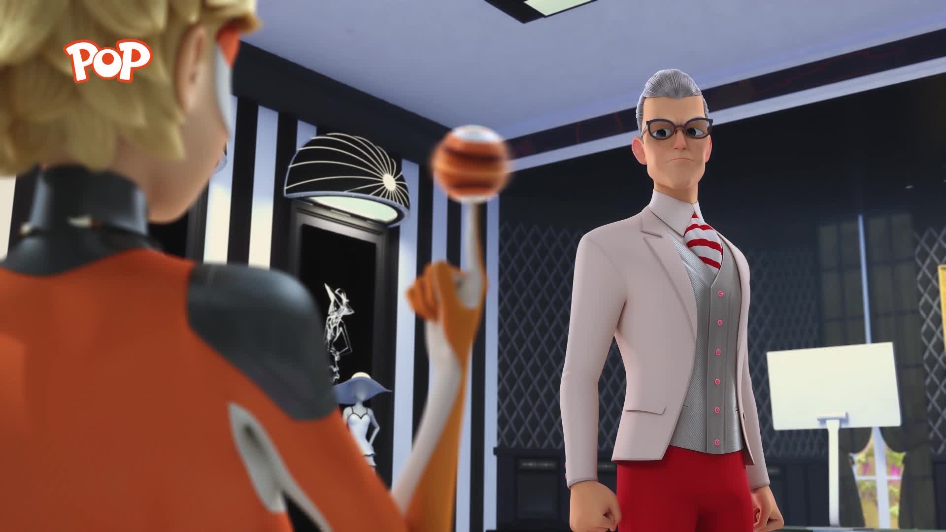 A young man in an orange suit balances a striped ball on his fingertip. He's facing a man in a cream suit, grey vest, and red trousers.