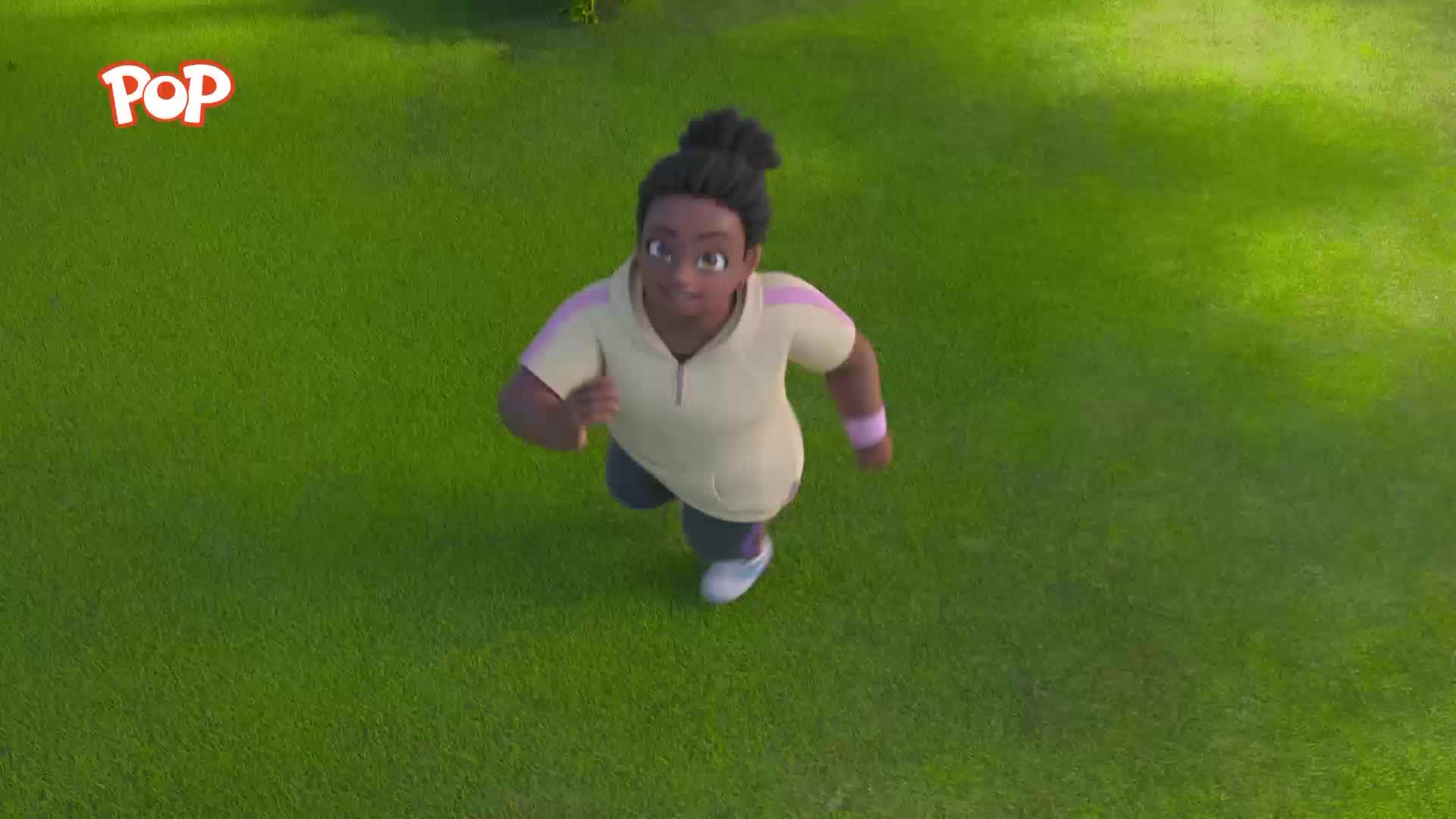 A young girl in a pale yellow top is running across a bright green field. She's got her hair tied up in a bun, and her arms are pumping as she goes.