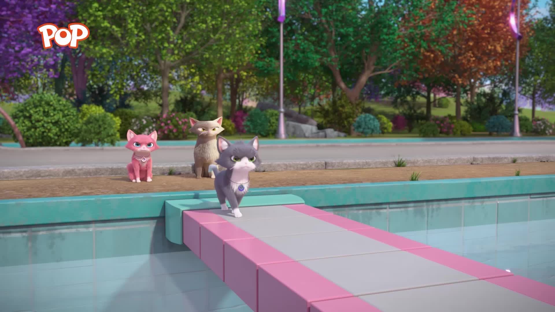 A grey kitten with a blue gem on its collar walks across a pink and grey ramp. Behind it, a tan cat sits patiently, and a pink kitten stands alert.