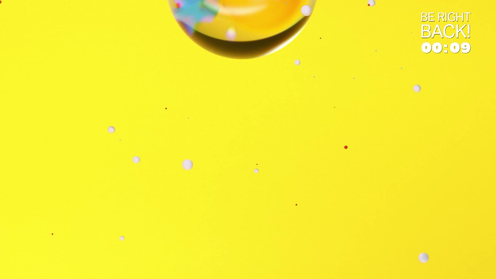 A large, iridescent sphere descends against a bright yellow backdrop. Tiny white and red specks drift around it. A large, iridescent sphere descends against a bright yellow backdrop. Tiny white and red specks drift around it.