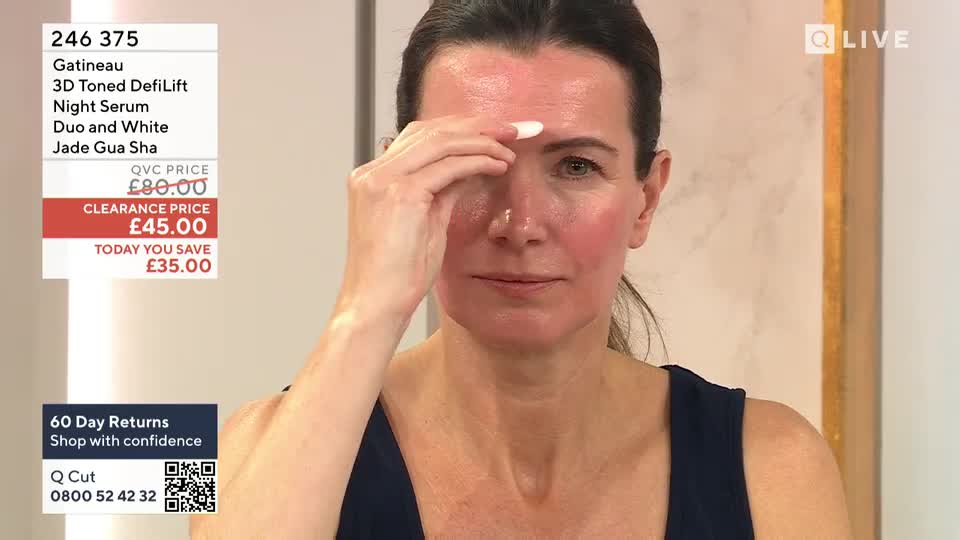 A woman on QVC Beauty in the United Kingdom gently touches her forehead, her skin appearing flushed. The screen displays product information, including a clearance price.
