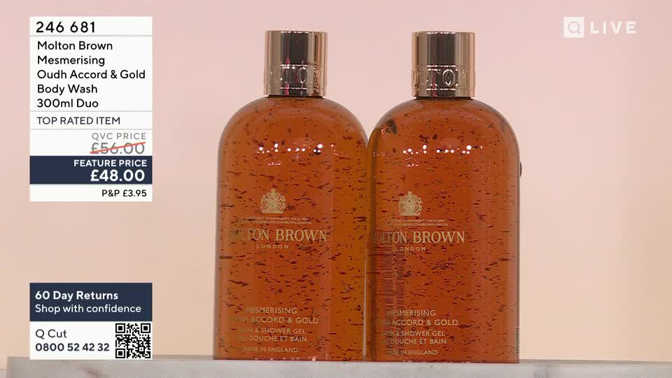 Two amber-colored Molton Brown body wash bottles, speckled with what looks like gold flakes, stand side-by-side. The QVC Beauty presentation highlights a "feature price" on the duo, with a price of £48.00.
