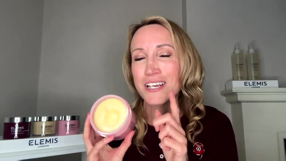 A woman in the UK, likely on QVC Beauty, holds up a jar of product, pointing with a smile. Behind her, more Elemis skincare products are neatly arranged.
A woman in the UK, likely on QVC Beauty, holds up a jar of product, pointing with a smile. Behind her, more Elemis skincare products are neatly arranged.