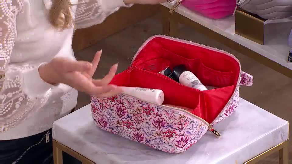 A presenter in a white lace top gestures towards a floral-patterned cosmetics bag. Inside, the bag's bright red lining holds several beauty products.
