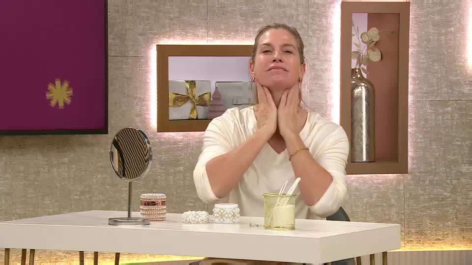 A woman in a cream-colored top gently massages her neck with both hands. She's seated at a white table, presumably demonstrating a beauty technique on a QVC UK broadcast.
A woman in a cream-colored top gently massages her neck with both hands. She's seated at a white table, presumably demonstrating a beauty technique on a QVC UK broadcast.