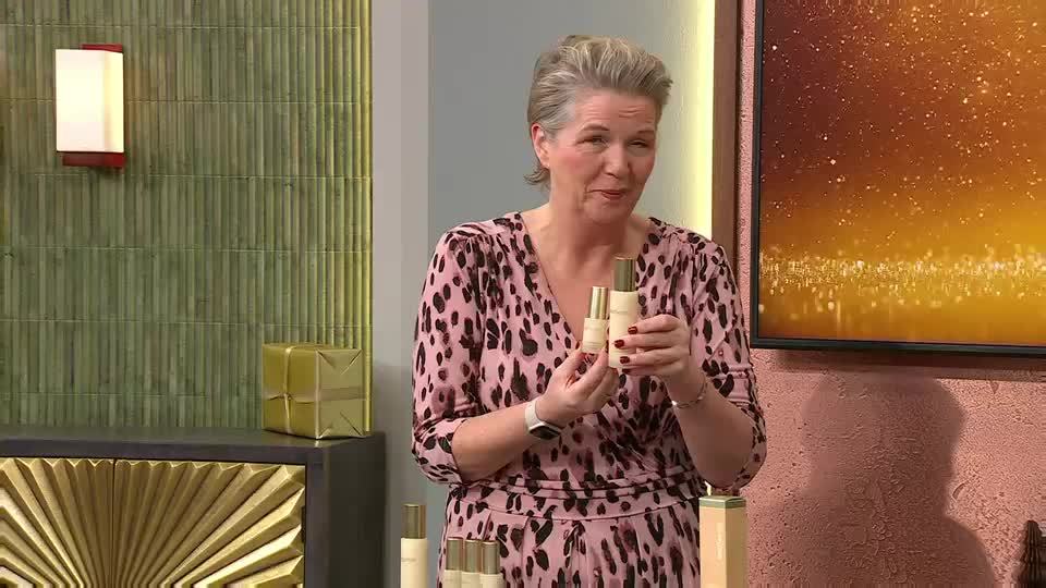 A woman in a pink leopard print top holds up two bottles of product, gesturing towards them. She's on a QVC Beauty set in the UK, with more bottles lined up on a table in front of her.
A woman in a pink leopard print top holds up two bottles of product, gesturing towards them. She's on a QVC Beauty set in the UK, with more bottles lined up on a table in front of her.