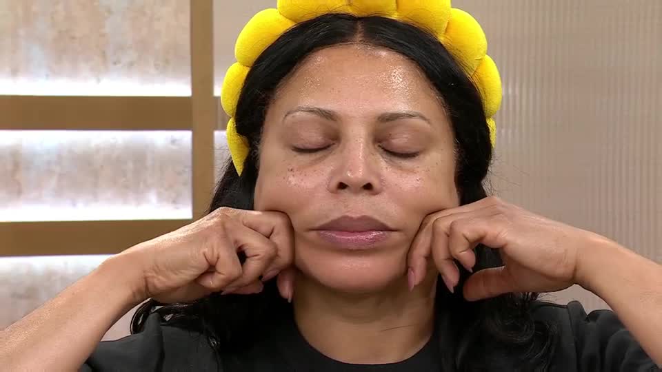 Her fingers gently press into her cheeks, her eyes closed as she focuses on the sensation. She's demonstrating a facial massage technique, likely for a QVC Beauty segment. Her fingers gently press into her cheeks, her eyes closed as she focuses on the sensation. She's demonstrating a facial massage technique, likely for a QVC Beauty segment.