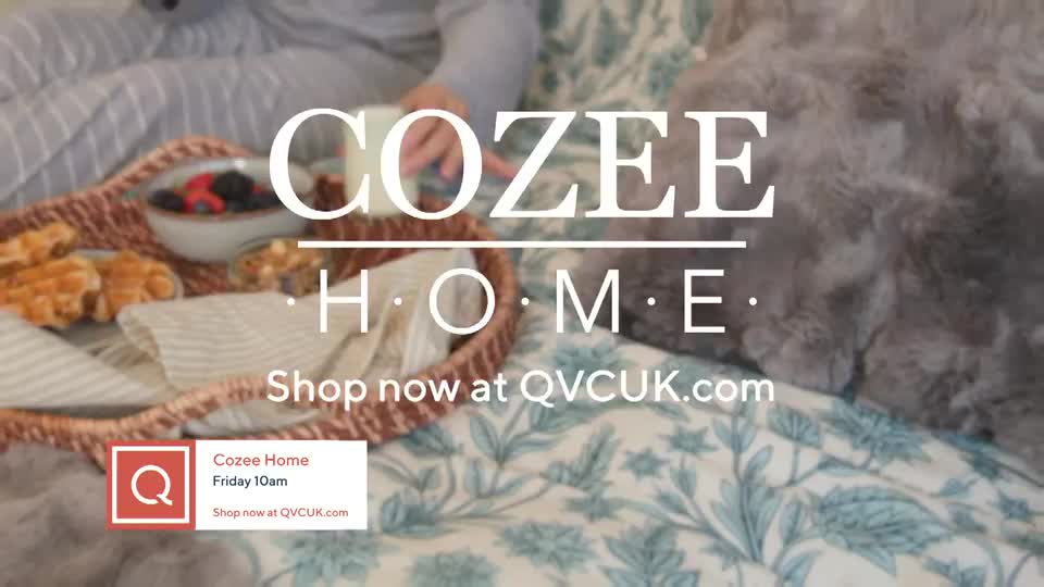 A tray with waffles and berries sits on a bed. The "Cozee Home" logo appears over the scene, with a prompt to shop at QVCUK.com.