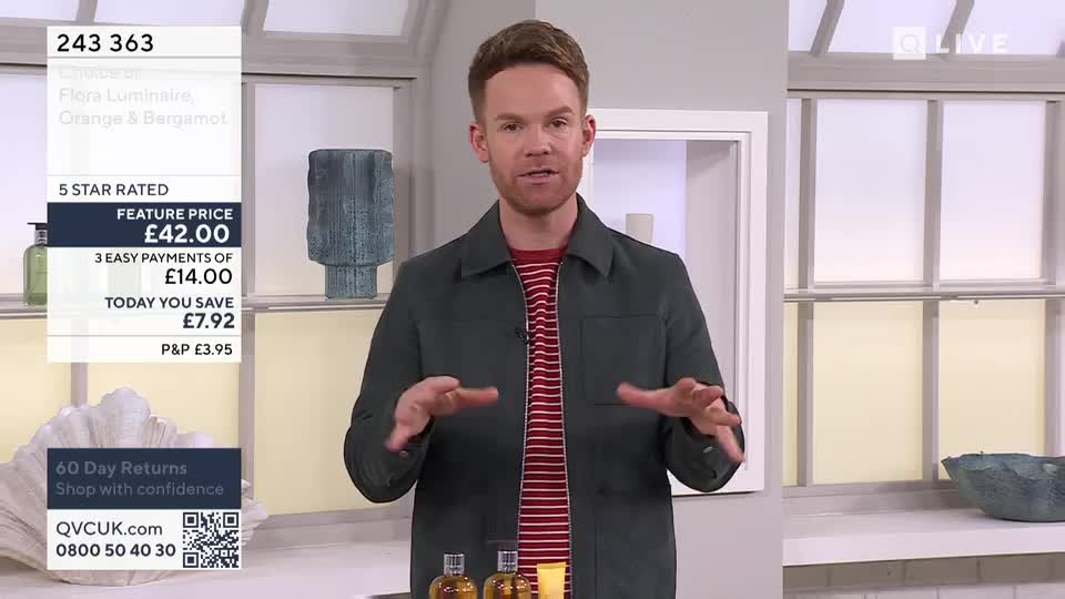 A man in a grey jacket and striped shirt gestures with his hands on a QVC beauty segment. He's presenting a product with a price of £42.00.