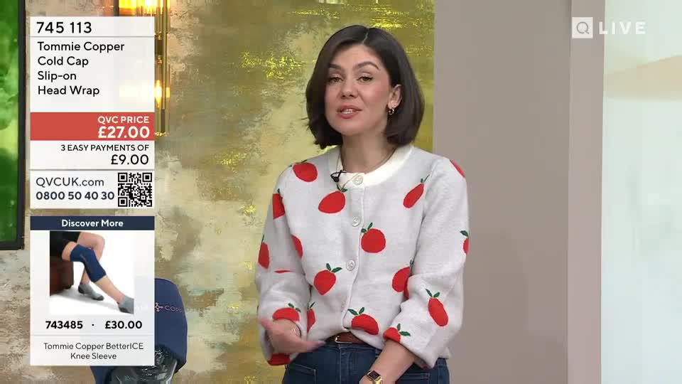 A woman in a strawberry-patterned cardigan gestures as she speaks, with product information for a Tommie Copper cold cap displayed on a screen beside her. A separate screen shows a Tommie Copper knee sleeve.