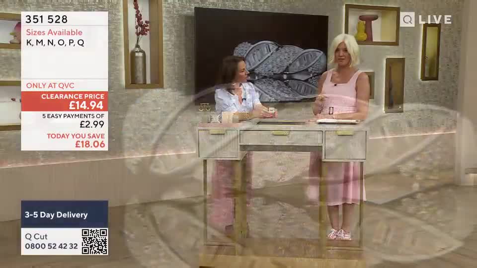 Two women are seated at a desk, one in a pink dress gesturing towards the camera, and the other in a white shirt looking on. A graphic displays the price of an item on QVC Extra.
