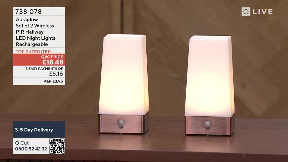 Two glowing, rectangular night lights sit side-by-side on a wooden surface. The QVC Extra logo is visible in the top right corner, and the price is listed as £18.48.
