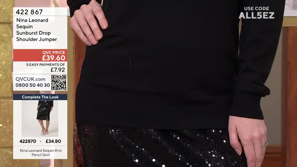 A woman in a black sweater and sequined skirt stands before a QVC Extra backdrop. The screen displays the price of the "Sunburst Drop Shoulder Jumper" in British pounds.
