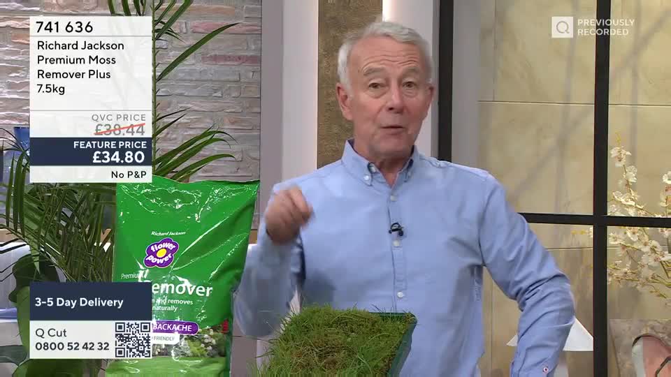 A man in a light blue shirt gestures enthusiastically, holding a square of vibrant green turf. Beside him, a large green bag of Richard Jackson's Premium Moss Remover Plus sits on display, detailing its feature price of £34.80.
