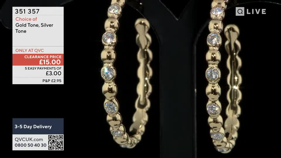 A pair of gold-toned hoop earrings, studded with clear stones, are displayed against a black backdrop. The QVC screen shows the clearance price and payment options for the jewelry.
