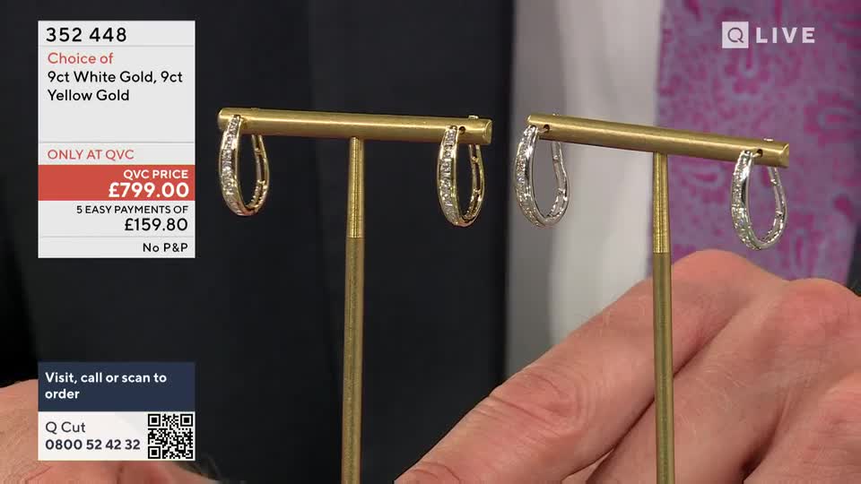 Two diamond-studded hoop earrings hang on gold stands, one in yellow gold and the other in white. A hand is holding the stand with the white gold earring, likely for a closer look on QVC.

