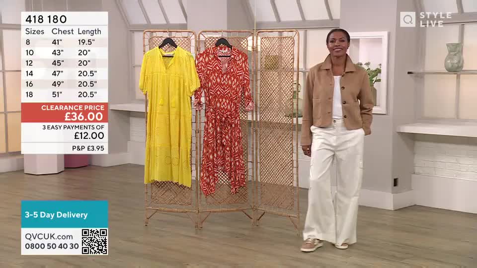 A presenter in a tan jacket and white trousers stands in front of a screen, with a yellow dress and a red patterned dress hanging behind her. The QVC UK logo is visible in the corner, and a price tag for the yellow dress is displayed on the left.
