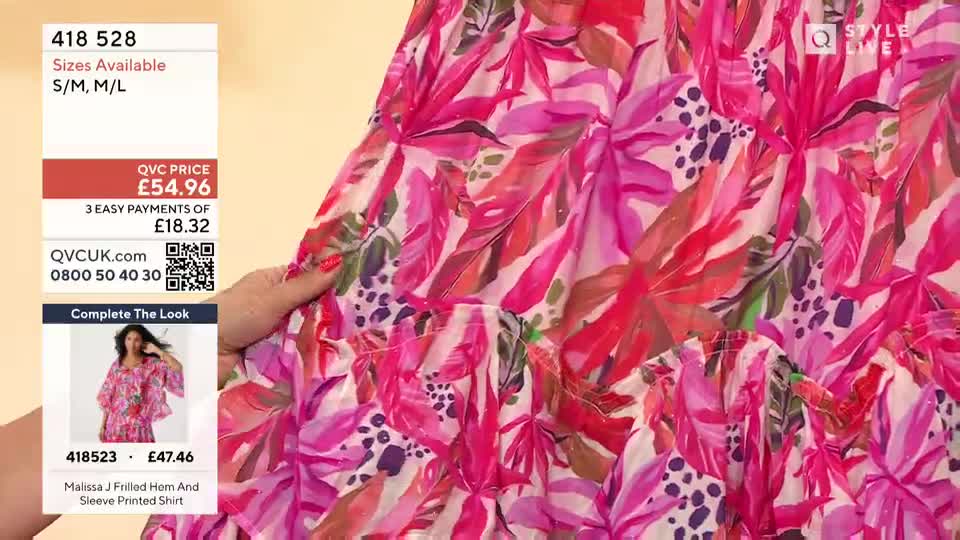 A hand with red nail polish gently holds up a flowing, tiered garment, showing off its bright pink floral print. The QVC price and product details are displayed in the corner.
