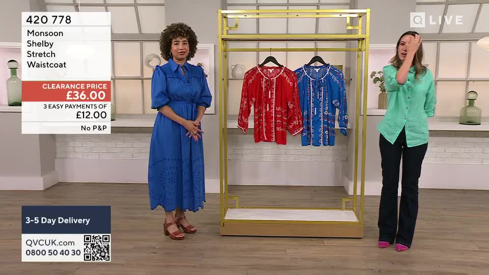Two women stand in a brightly lit studio, one in a blue dress and the other in a green shirt, both gesturing toward a rack of colorful tops. A screen displays the price of a "Shelby Stretch Waistcoat" on a clearance sale.
