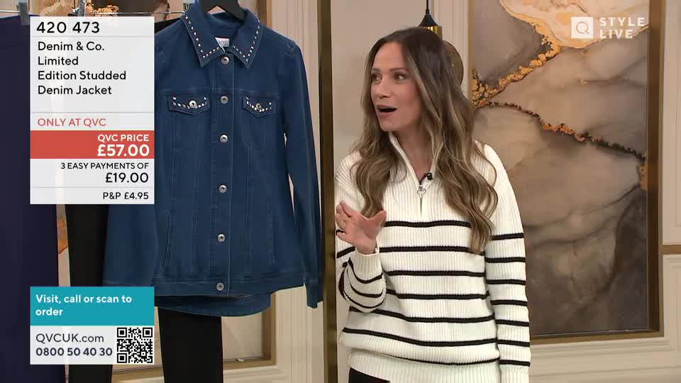 A woman in a striped sweater gestures towards a denim jacket studded with rhinestones. The jacket hangs on a rack, with a price tag and ordering information displayed beside it.
