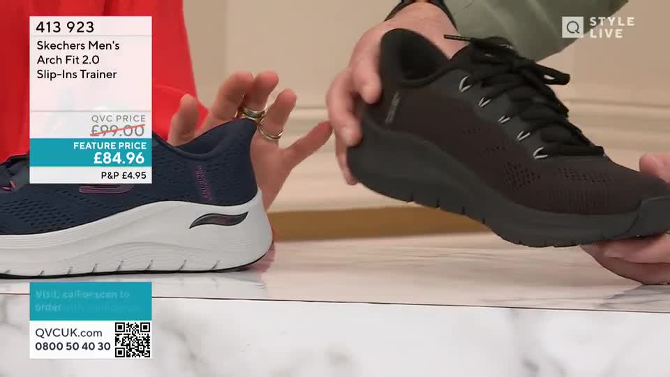 A presenter on QVC is holding up a black Skechers trainer, showing off its features. Beside it, a navy blue and white shoe sits, with the price and details displayed on a screen.
