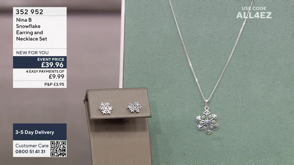 A silver snowflake pendant hangs on a delicate chain next to matching stud earrings, all displayed against a muted backdrop. The on-screen text in the style of QVC, details the price and offers a discount code for the jewelry set.
