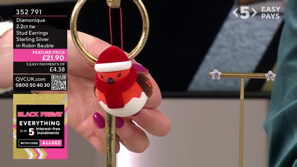 A hand holds a miniature robin ornament, its red scarf and hat a festive touch. Beside it, a pair of star-shaped earrings sit on a gold stand, ready to be showcased.
A hand holds a miniature robin ornament, its red scarf and hat a festive touch. Beside it, a pair of star-shaped earrings sit on a gold stand, ready to be showcased.