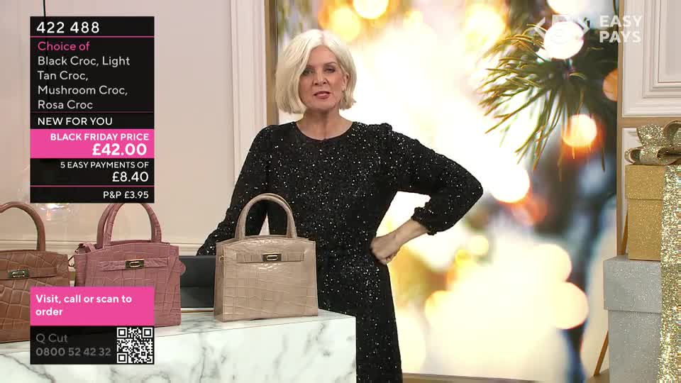 A woman in a sparkly black dress stands next to a selection of handbags, the prices and options displayed on screen. She's in a QVC-style studio, likely presenting a Black Friday offer.
A woman in a sparkly black dress stands next to a selection of handbags, the prices and options displayed on screen. She's in a QVC-style studio, likely presenting a Black Friday offer.