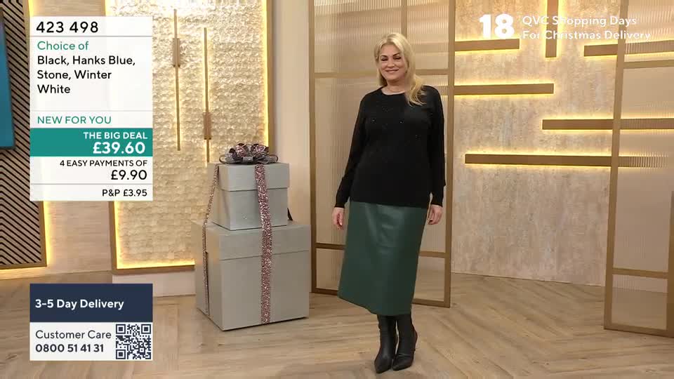 A woman in a black top and green skirt stands in front of a backdrop, likely on a QVC set. She's posing near a stack of gift boxes, and the screen shows the price of the outfit.
A woman in a black top and green skirt stands in front of a backdrop, likely on a QVC set. She's posing near a stack of gift boxes, and the screen shows the price of the outfit.