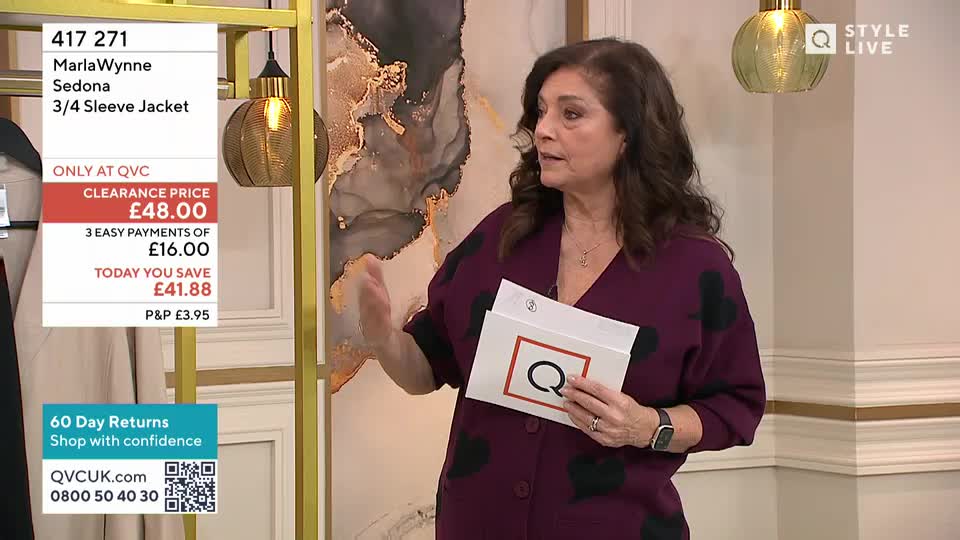 A woman in a plum cardigan with black hearts gestures with her right hand while holding a white card with a large red 'Q' on it. A price tag for a jacket hangs to her left, displaying a clearance price of £48.00.