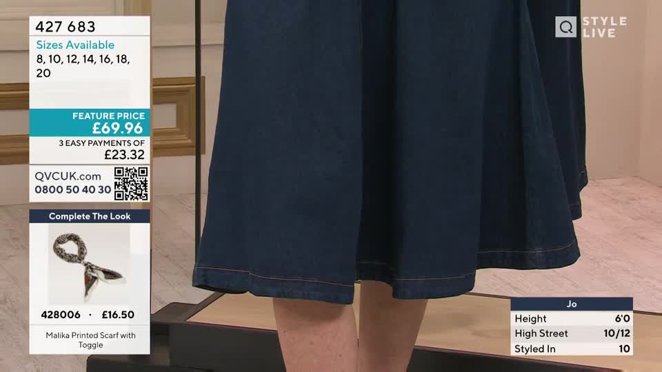 The dark denim skirt flares out slightly as the presenter shifts her weight. A small, patterned scarf is displayed below, ready to complete the look.