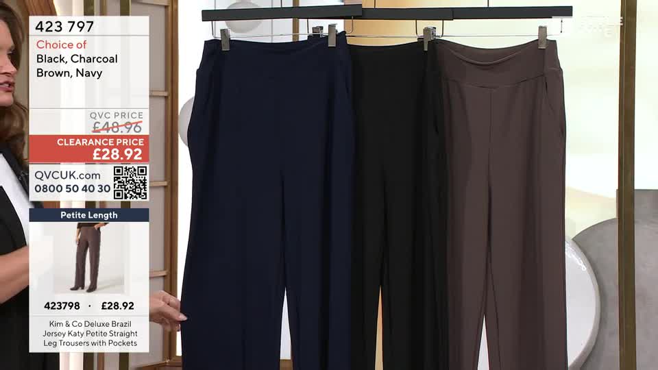 A woman's hand reaches out to touch a pair of navy blue trousers hanging on a rail. Three pairs of trousers, in navy, black, and brown, are displayed side-by-side.