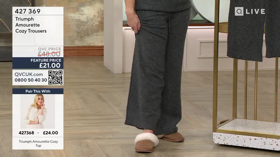 A woman stands in wide-legged grey trousers and fluffy slippers. A graphic overlay displays product details and pricing from QVC.