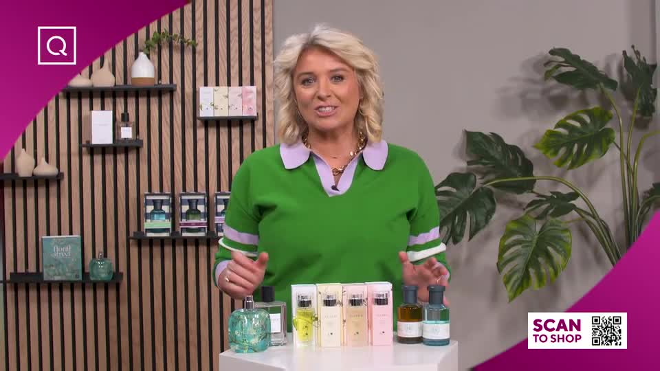 A woman in a bright green jumper gestures towards a display of perfume bottles. The shelves behind her hold more fragrances and decorative items. A woman in a bright green jumper gestures towards a display of perfume bottles. The shelves behind her hold more fragrances and decorative items.
