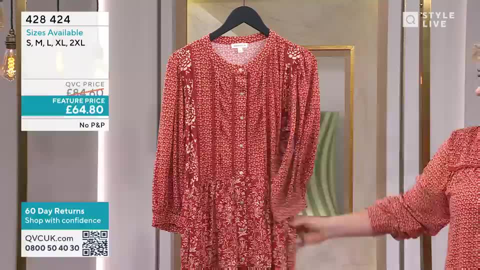 A hand reaches out to adjust the sleeve of a red, floral-print dress hanging on a display. The screen shows pricing information and available sizes for the garment. A hand reaches out to adjust the sleeve of a red, floral-print dress hanging on a display. The screen shows pricing information and available sizes for the garment.