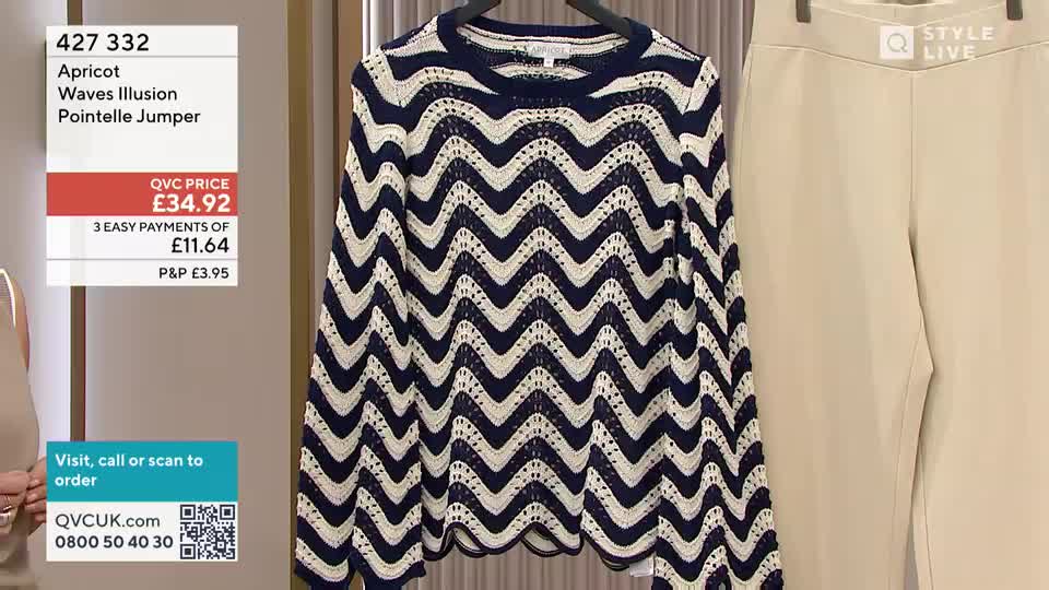 A navy and cream chevron-patterned jumper hangs on a rail. Beside it, a pair of pale beige trousers are displayed. A navy and cream chevron-patterned jumper hangs on a rail. Beside it, a pair of pale beige trousers are displayed.