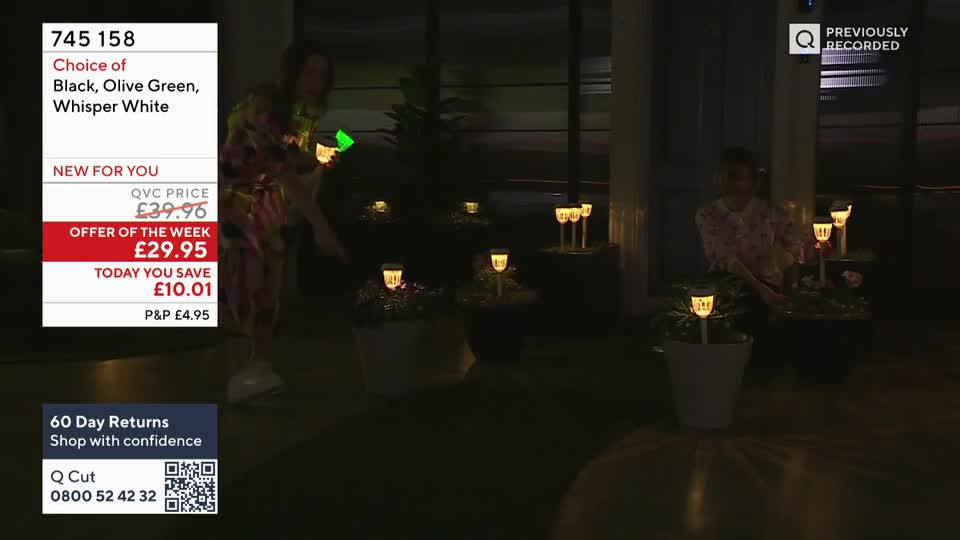 A woman in a colourful outfit is holding up a small, glowing solar light. Another woman, in a floral top, is tending to a pot of plants, each with a similar light.