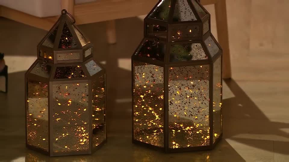 Two ornate lanterns, each with a mirrored surface, sit side-by-side. Tiny, warm lights twinkle inside, casting a soft glow on the wooden floor.
