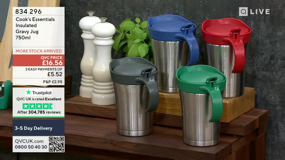 Four insulated gravy jugs with colorful lids and handles sit on a wooden surface, ready for a demonstration on QVC UK. Beside them, two white pepper grinders and some greenery add to the kitchen-themed display.
