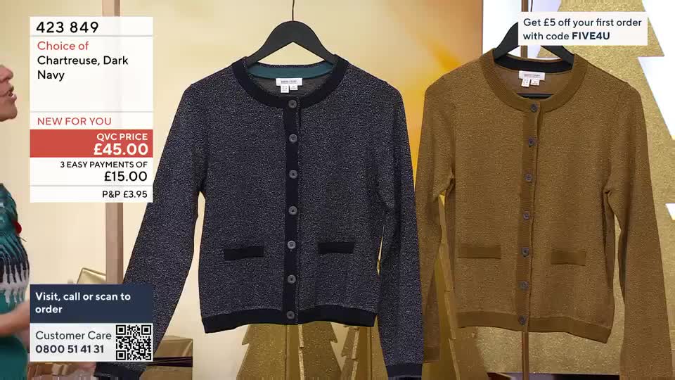 Two cardigans hang side-by-side, one navy, one mustard, both buttoned up on a black hanger. The QVC price is displayed onscreen, along with the option to pay in installments.

