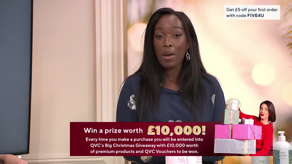 A woman on QVC in the United Kingdom is speaking directly to the camera, gesturing with her hands. Behind her, a graphic promotes a Christmas giveaway with a £10,000 prize.
