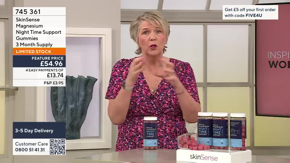 The presenter gestures enthusiastically while explaining the benefits of SkinSense Magnesium Night Time Support Gummies. Three bottles of the product stand on display, alongside a scattering of the pink, square gummies.