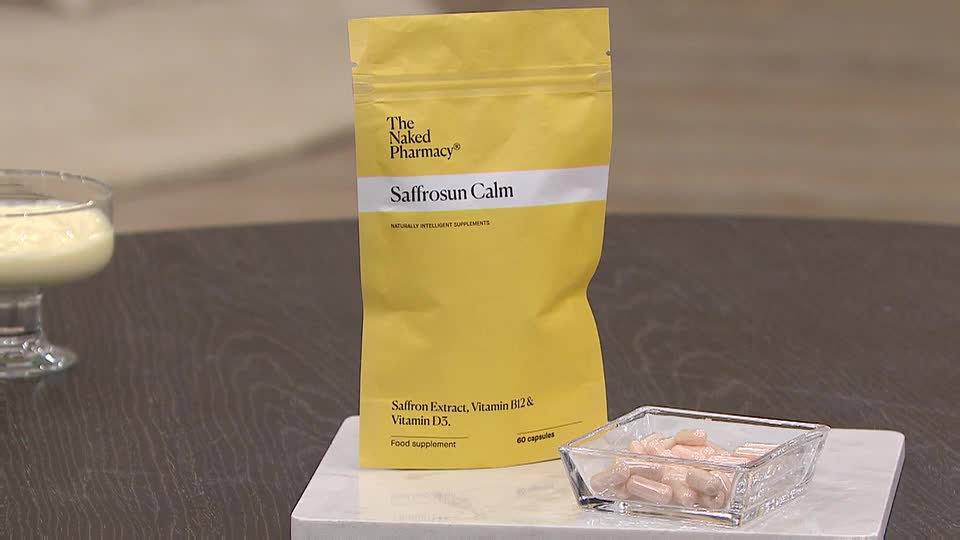 A bright yellow pouch of "Saffrosun Calm" supplements sits on a white marble slab. Beside it, a small glass dish holds a pile of pale pink capsules. A bright yellow pouch of "Saffrosun Calm" supplements sits on a white marble slab. Beside it, a small glass dish holds a pile of pale pink capsules.