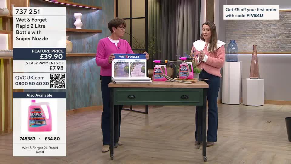 Two women stand behind a green table, presenting a cleaning product on QVC. One woman holds up a board showing a "before and after" of a garden path.