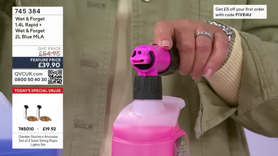 A hand grips a bright pink spray nozzle, attached to a bottle of pink liquid. The nozzle has a cartoonish face with wide eyes and a smiling mouth. A hand grips a bright pink spray nozzle, attached to a bottle of pink liquid. The nozzle has a cartoonish face with wide eyes and a smiling mouth.