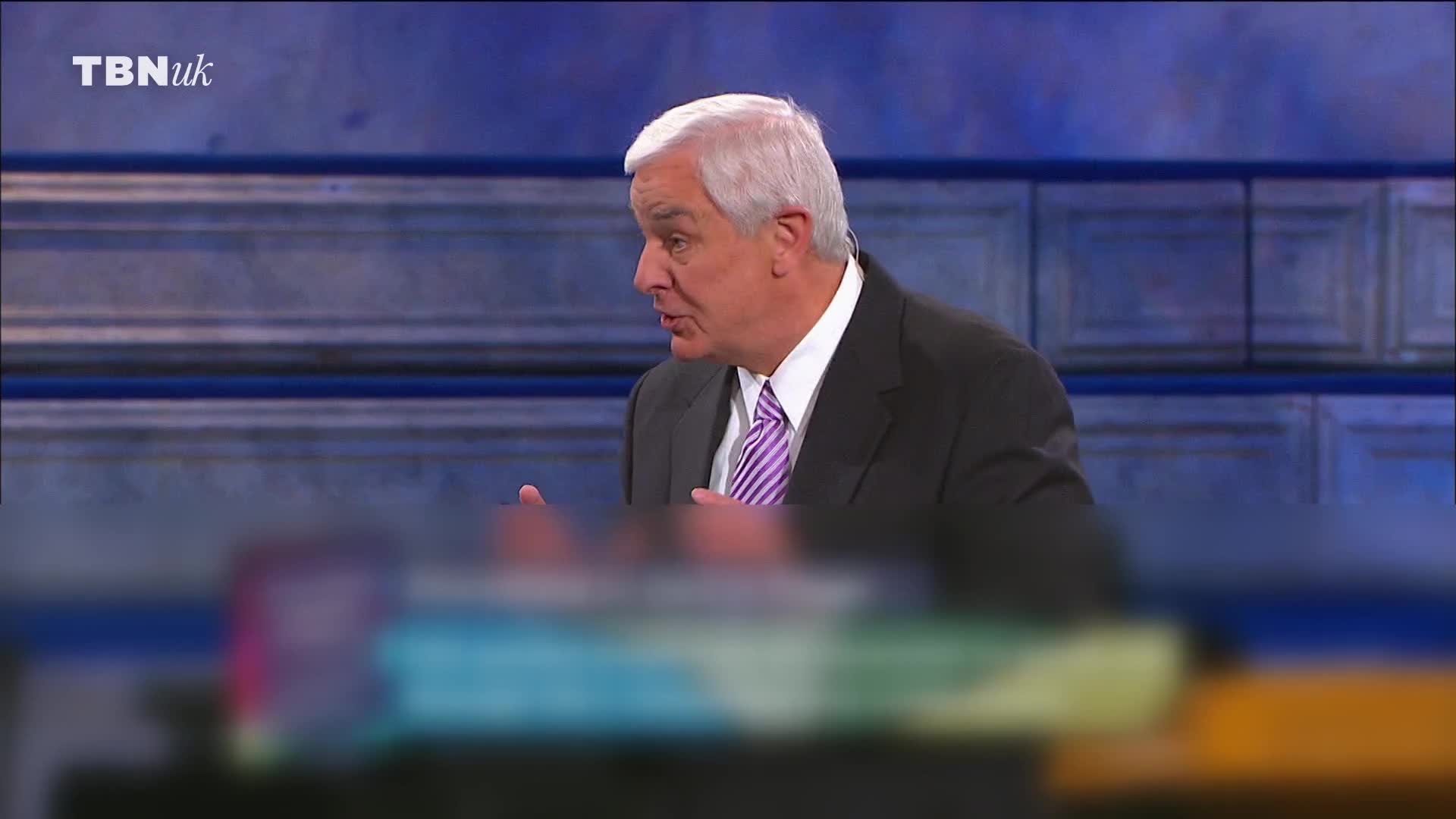 A man in a suit and tie is speaking, gesturing with his hands. The TBN UK logo is visible in the corner.
