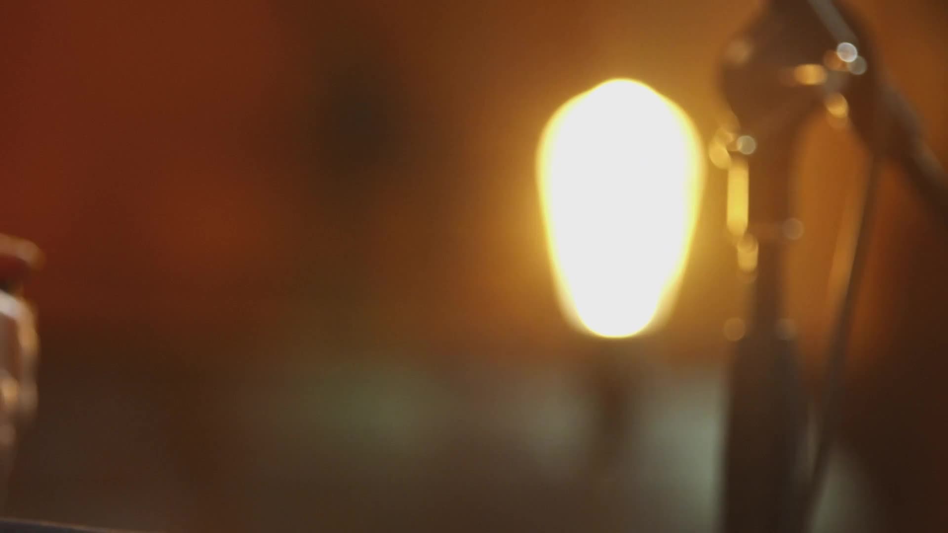 A bright light shines, casting a warm glow across the room. The microphone stands tall against the backdrop, its silhouette partially visible.
