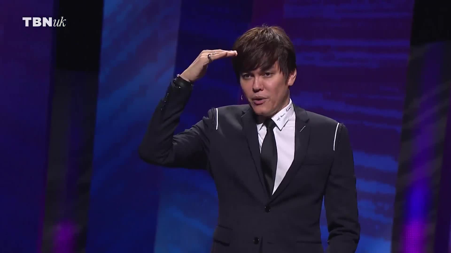 He's holding his hand up, palm forward, as if shielding his eyes. The man in the suit is speaking on a TBN UK stage.
He's holding his hand up, palm forward, as if shielding his eyes. The man in the suit is speaking on a TBN UK stage.