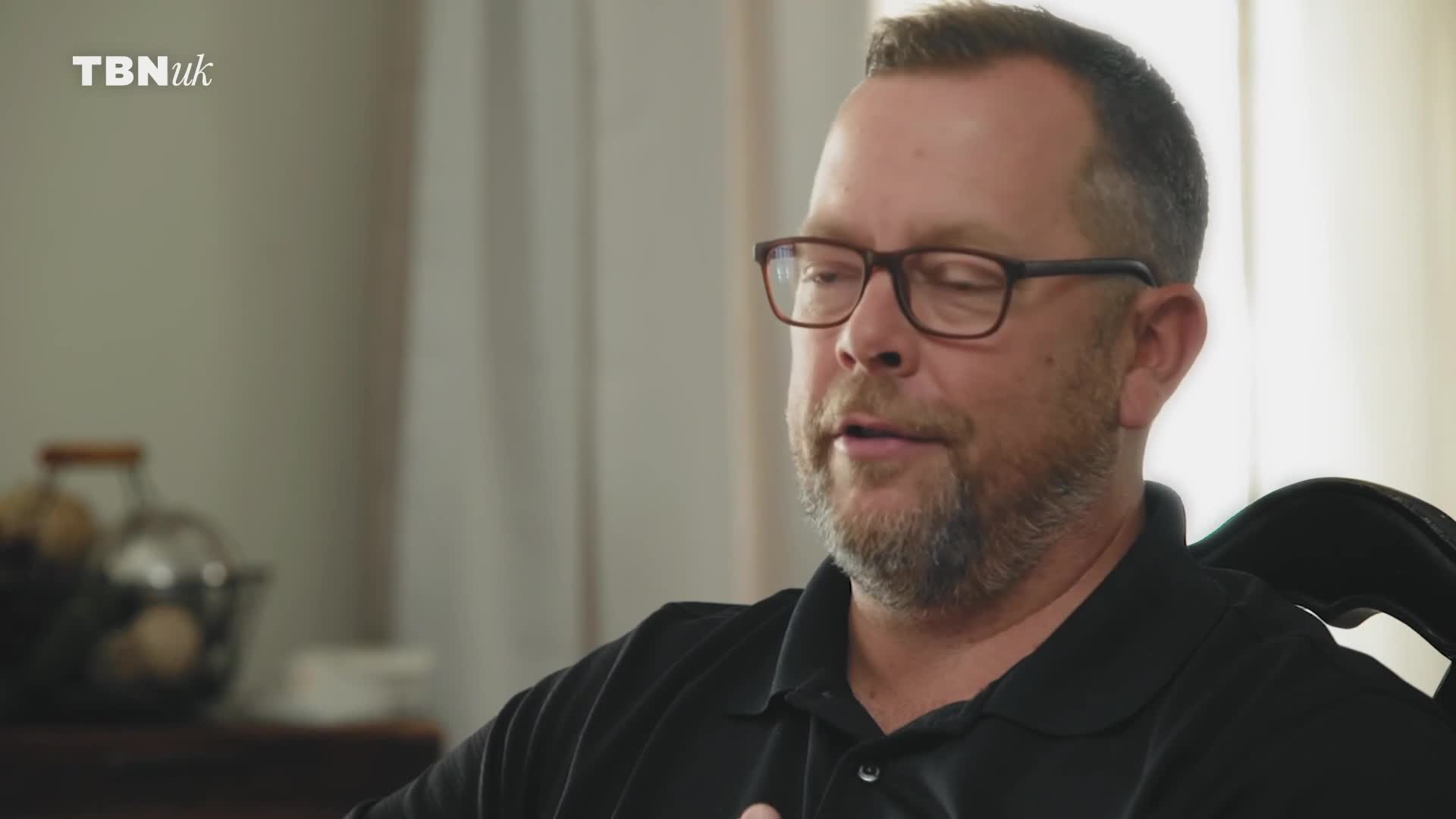 A man in glasses, seated, is speaking. The TBN UK logo is in the corner.
A man in glasses, seated, is speaking. The TBN UK logo is in the corner.
