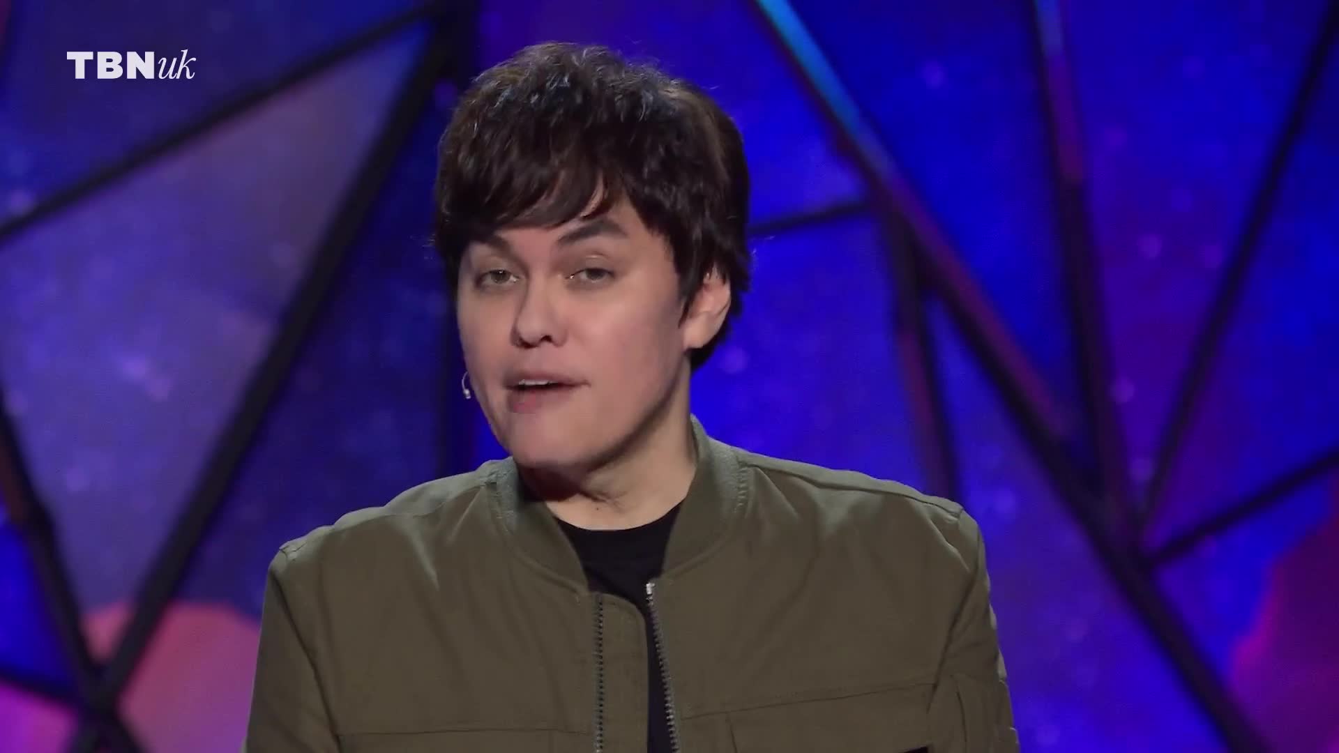 The person on the stage is speaking, their mouth moving as they address the audience. The TBN UK logo is in the corner, and the background is a vibrant blue.
The person on the stage is speaking, their mouth moving as they address the audience. The TBN UK logo is in the corner, and the background is a vibrant blue.